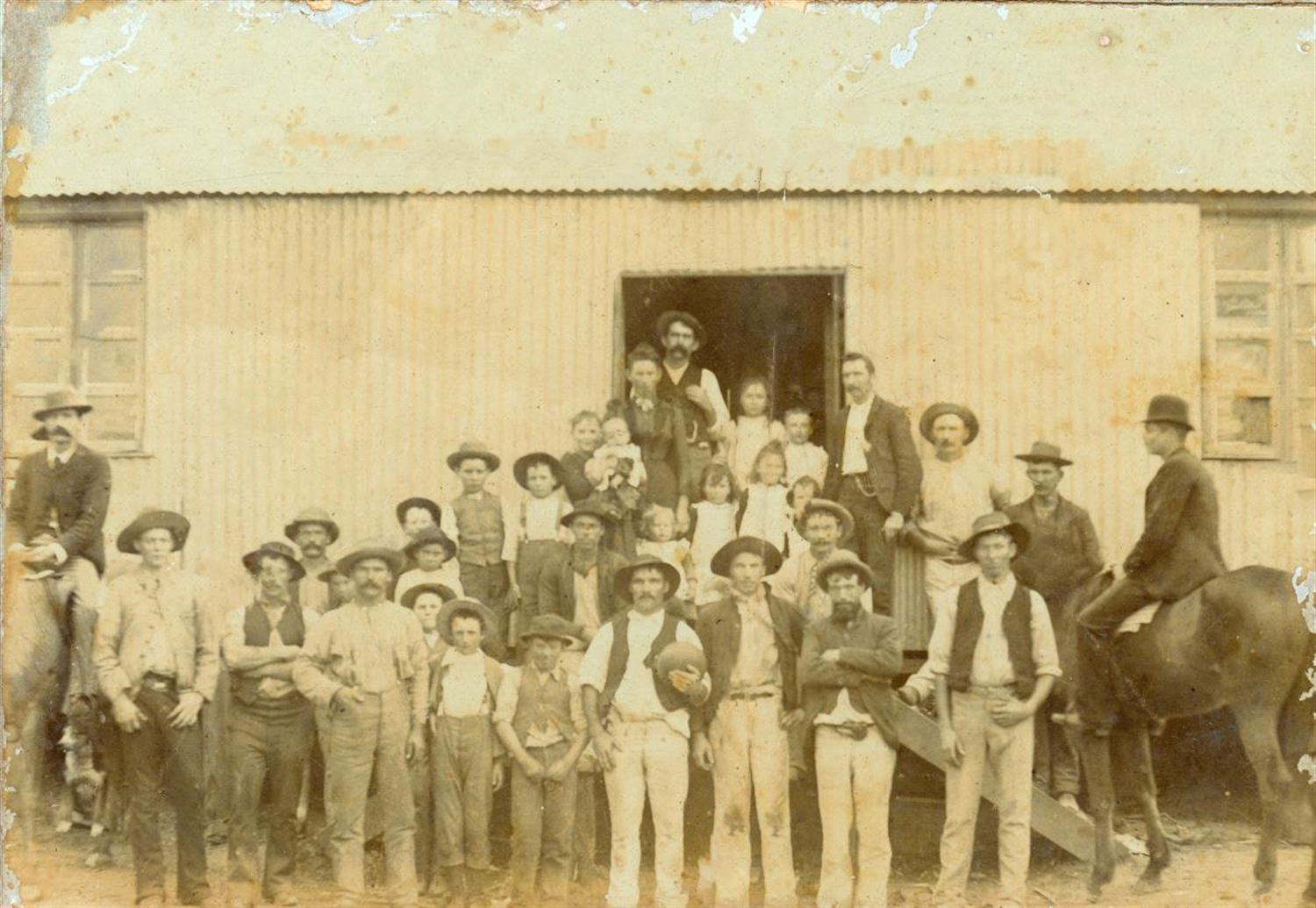 Group photograph of workers and families outside Burke's Store, Dunbible, during railway construction